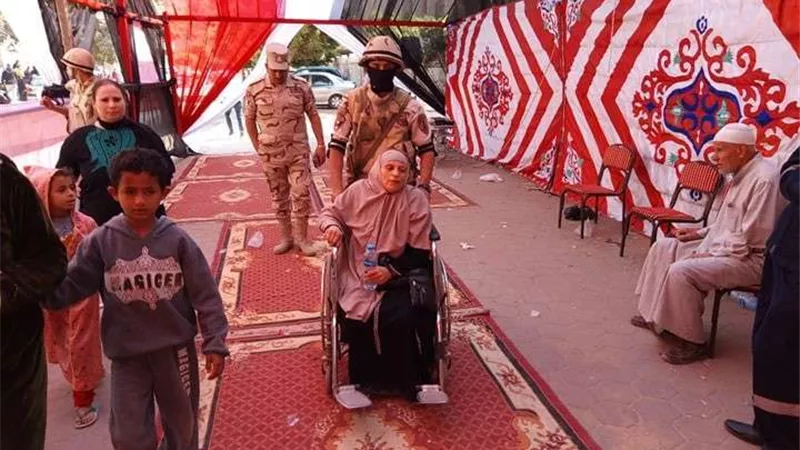 مُجند يساعد مُسنة للإدلاء بصوتها بـ 