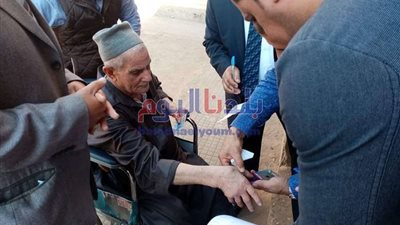 رئيس لجنة انتخابية يساعد مسن للإدلاء بصوته في مدينة المحلة (صور)